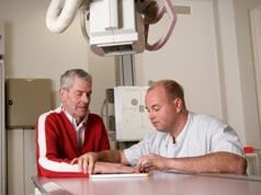 Radiodiagnostisch laborant legt uit aan een patiënt wat het onderzoek inhoudt.